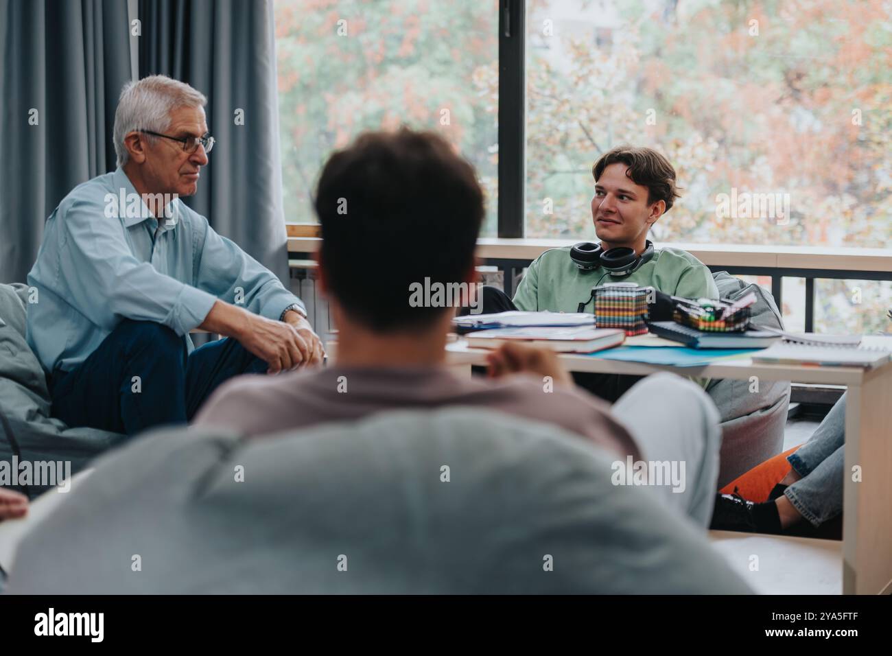 Professor engaging with attentive students in study lounge Stock Photo