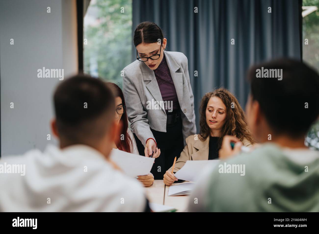 Teacher guiding students in classroom during group study session Stock Photo