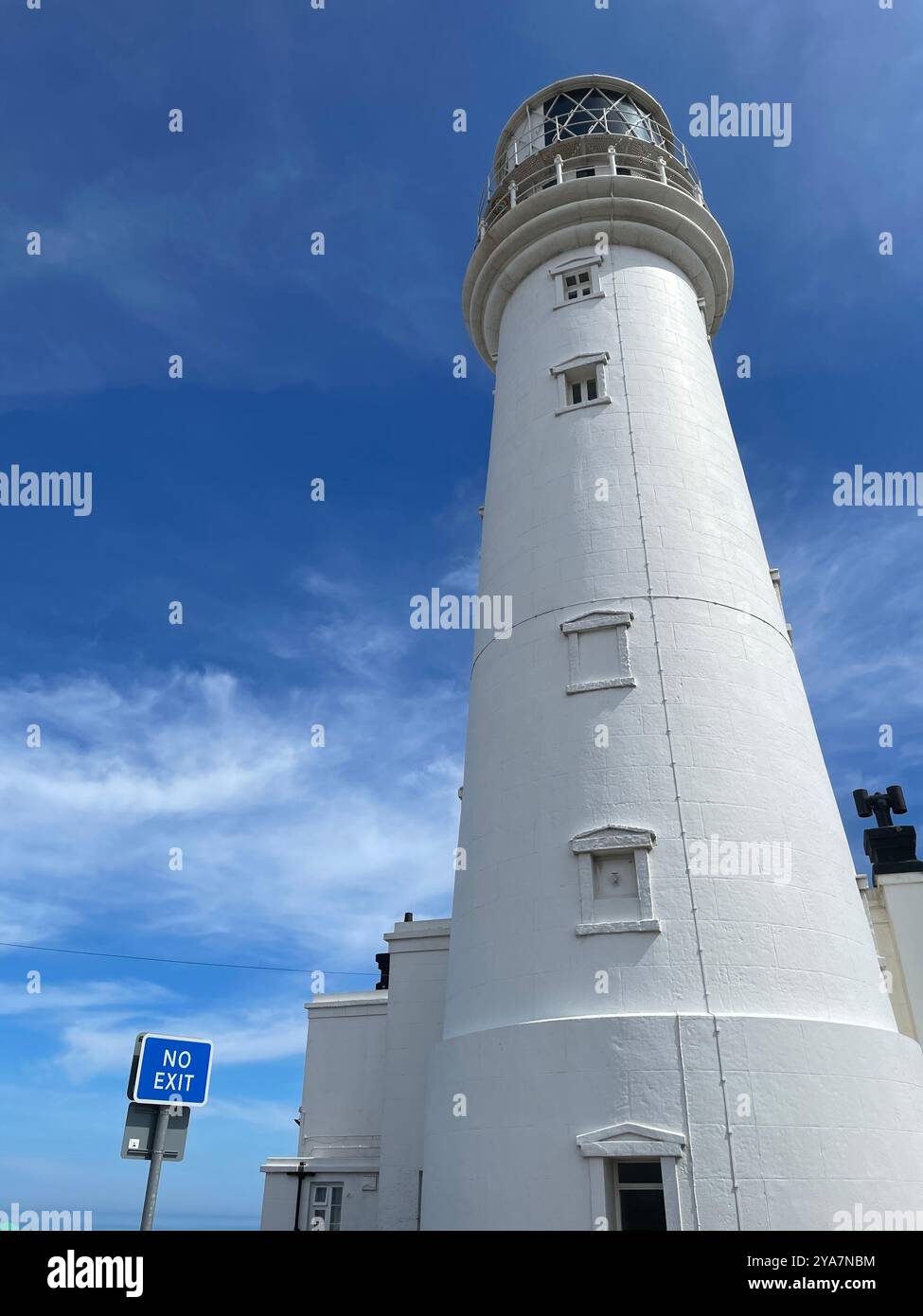 “Standing tall by the coast, the white lighthouse keeps watch under a clear blue sky, surrounded by golden grasses and the endless horizon.” - Smartphone Captured Stock Image