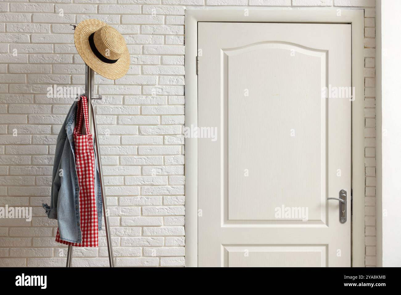 Metal rack with clothes and straw hat in hallway Stock Photo - Alamy