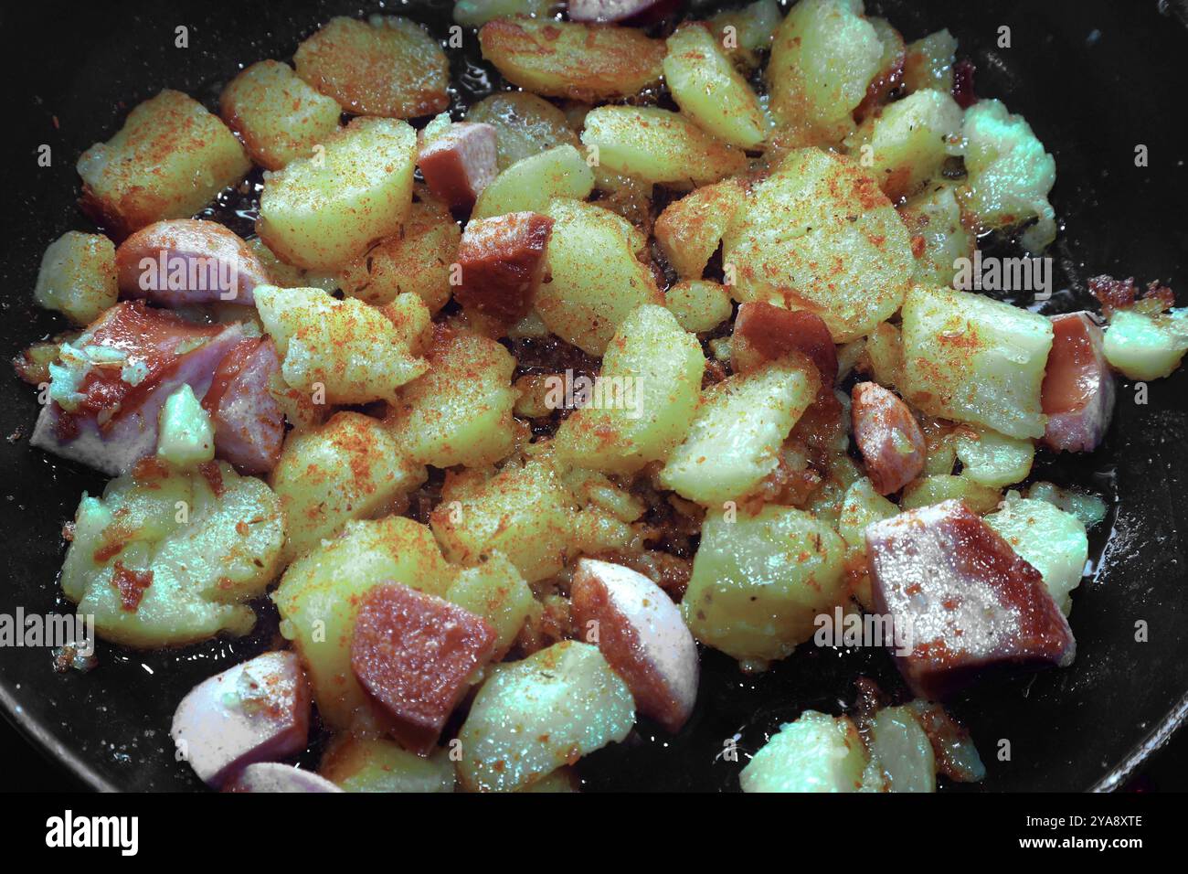 Deftige Mahlzeiten aus der Kartoffel Kartoffeln in heißem Öl während der Zubereitung zu deftigen Bratkartoffeln mit Ei und Fleischwurst. *** Hearty meals from the potato Potatoes in hot oil during preparation to make hearty fried potatoes with egg and sausage Stock Photo