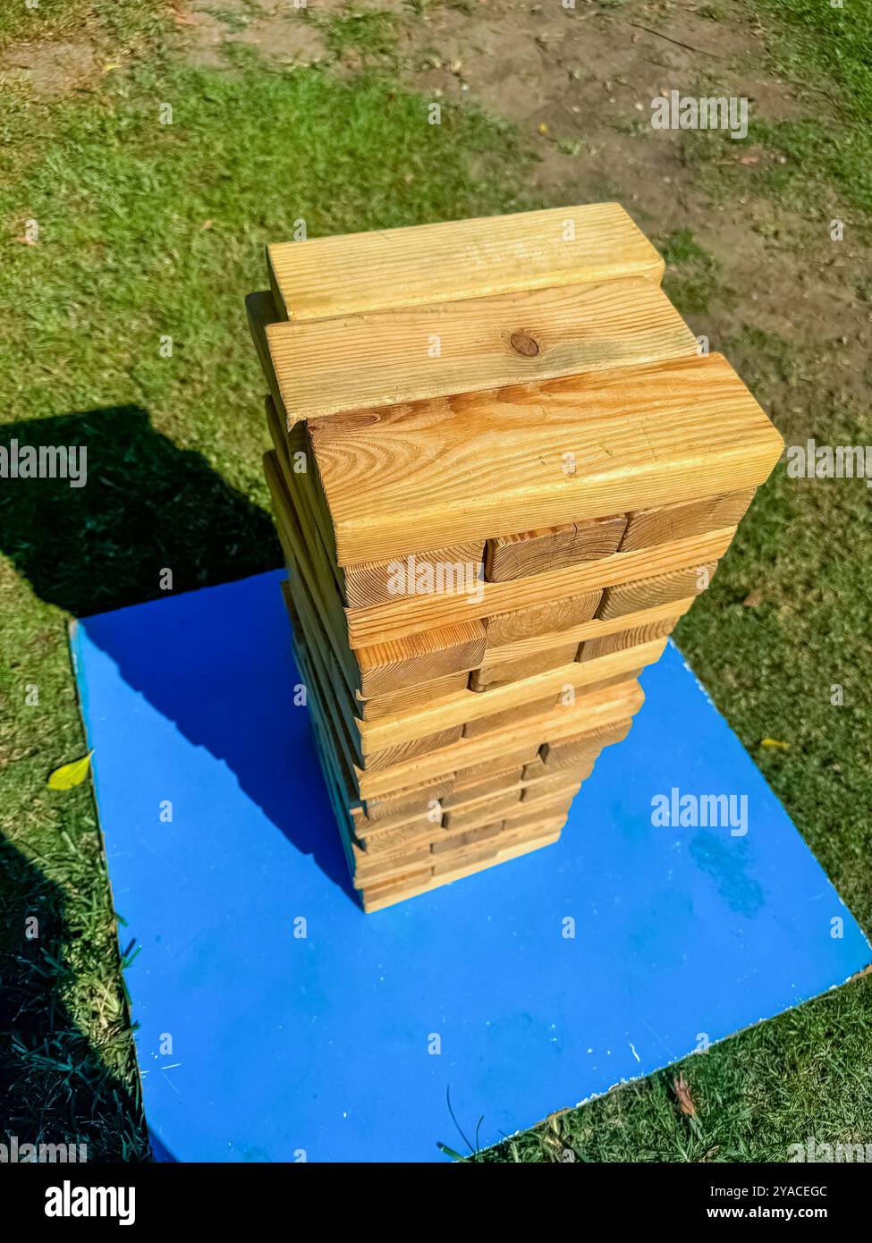 Outdoor wooden Jenga tower on a blue platform, ready for a fun garden