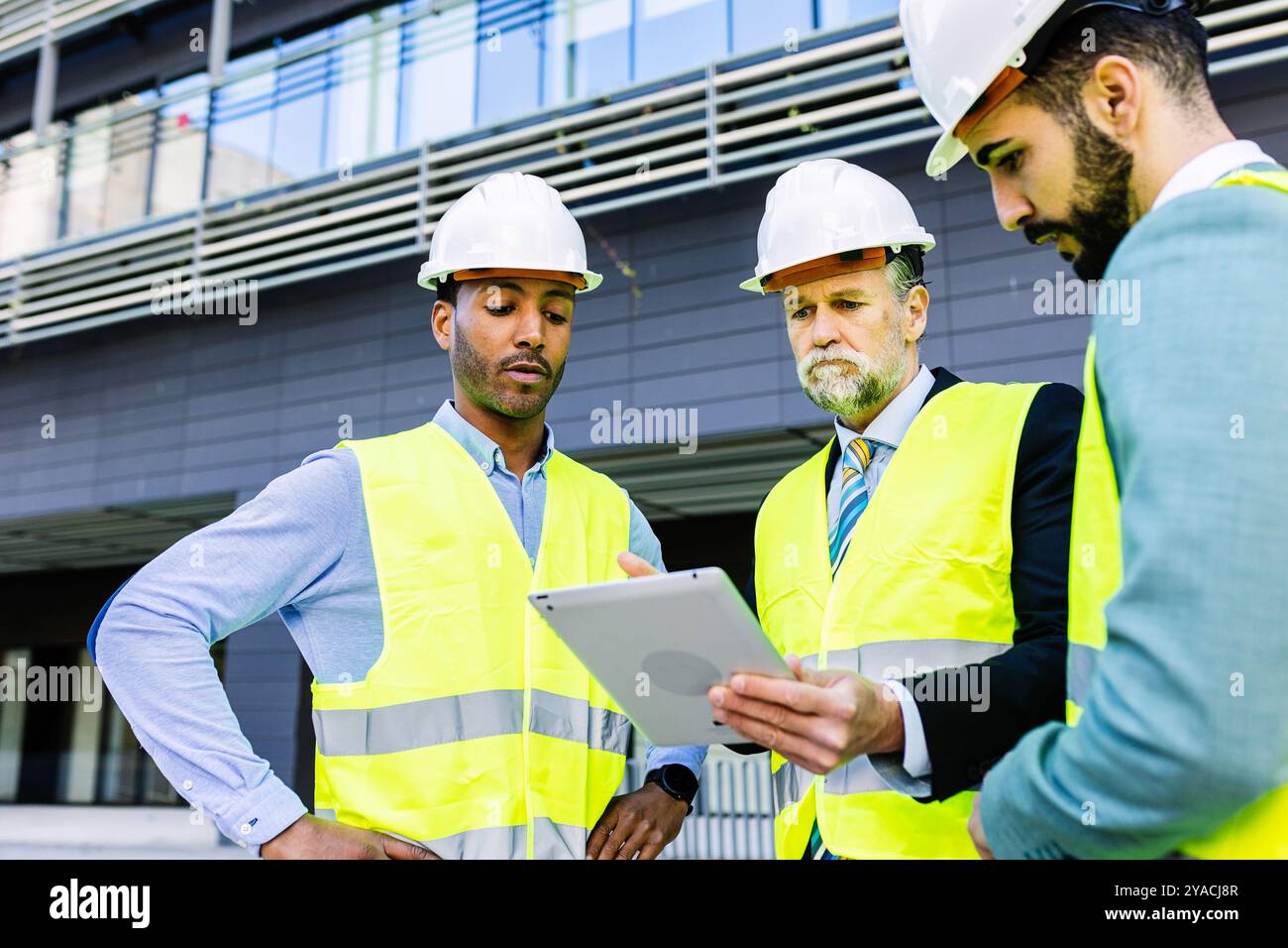 Construction site manager using tablet while having a discussion with colleagues Stock Photo