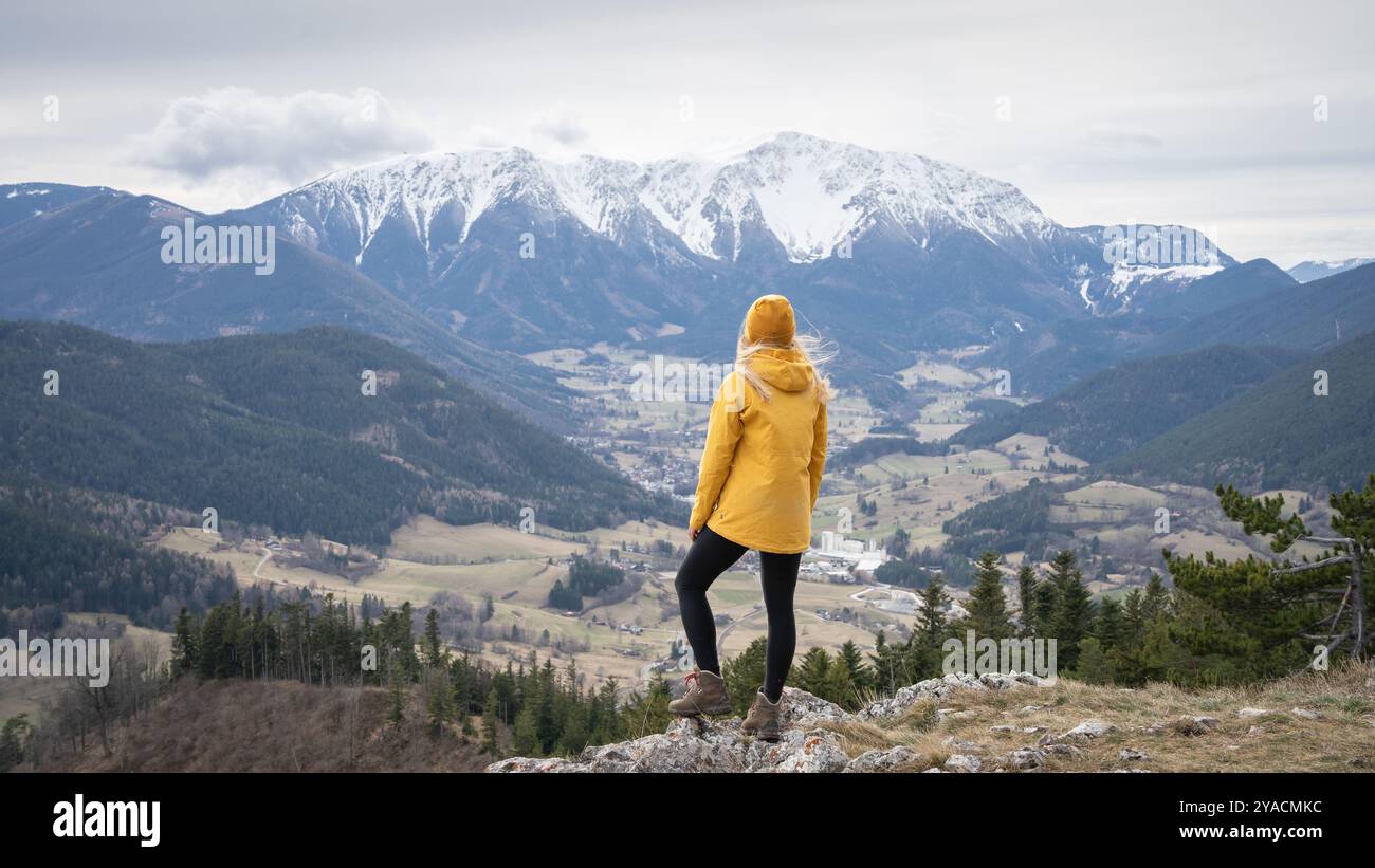 Female hiker on the top of the mountain enjoying the view on snowy peak in background, Austrian Alps Stock Photo