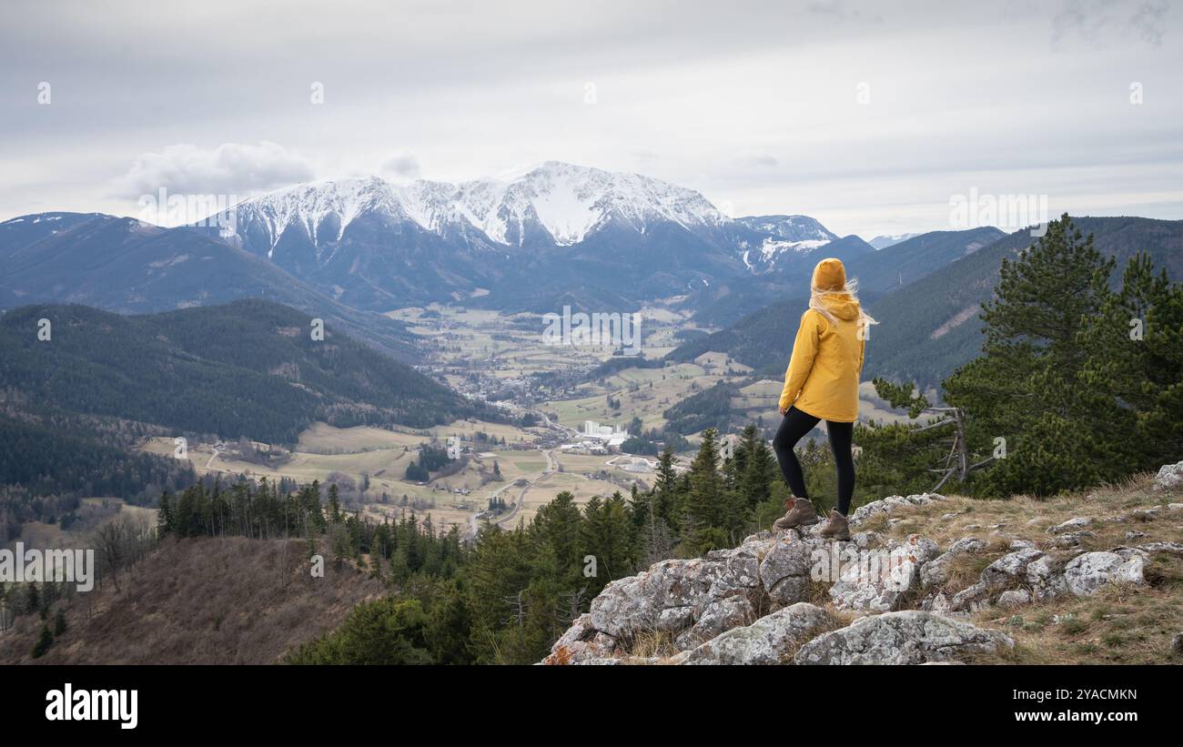 Female hiker on the top of the mountain enjoying the view on snowy peak in background, Austrian Alps Stock Photo