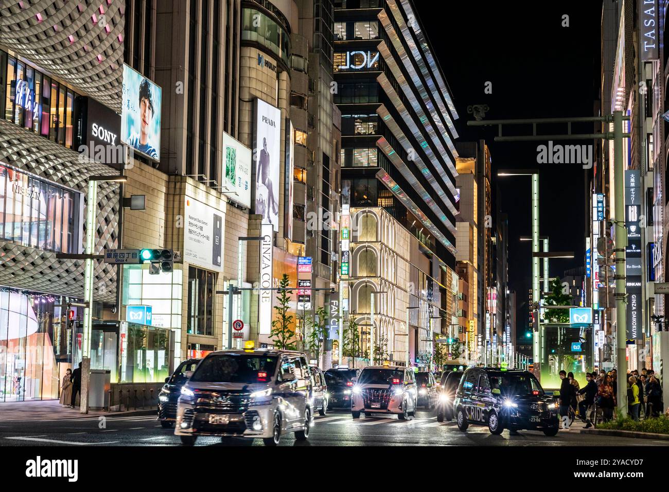 Traffic crossing the famous Ginza 4 crossroads at night with background of the Ginza Core and Ginza Six buildings. Metro station entrances. Night. Stock Photo