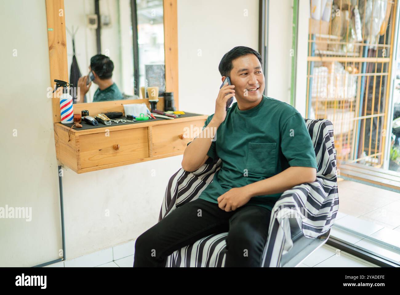 A man is in a barber shop talking on a cell phone Stock Photo