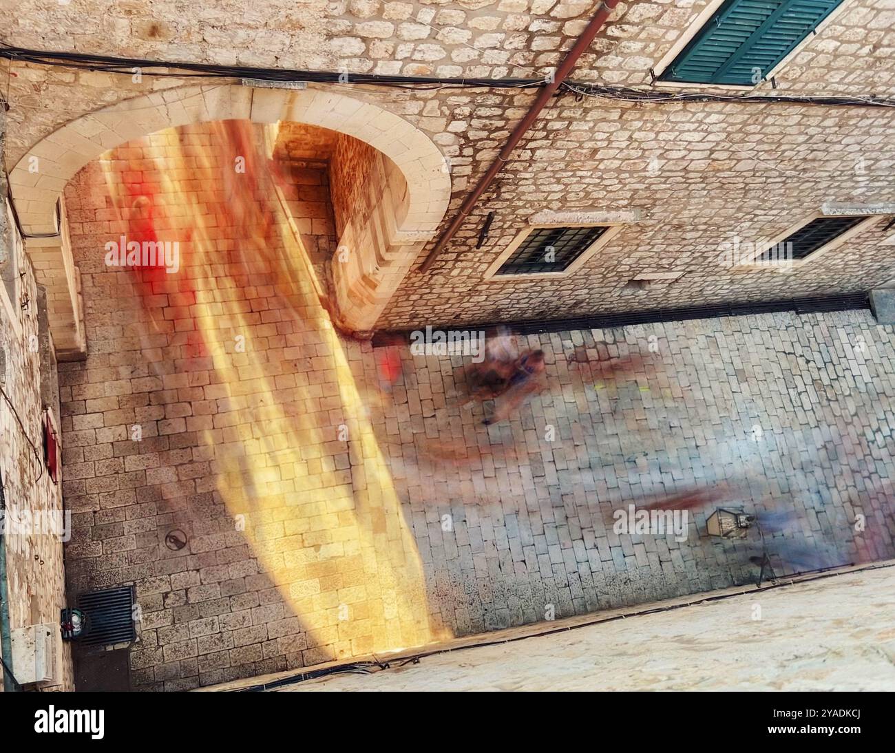 Blur of people caught in light passing through archway under the bell tower on Stadun. Viewed from the city walls of the old town Dubrovnik, Croatia - Smartphone Captured Stock Image