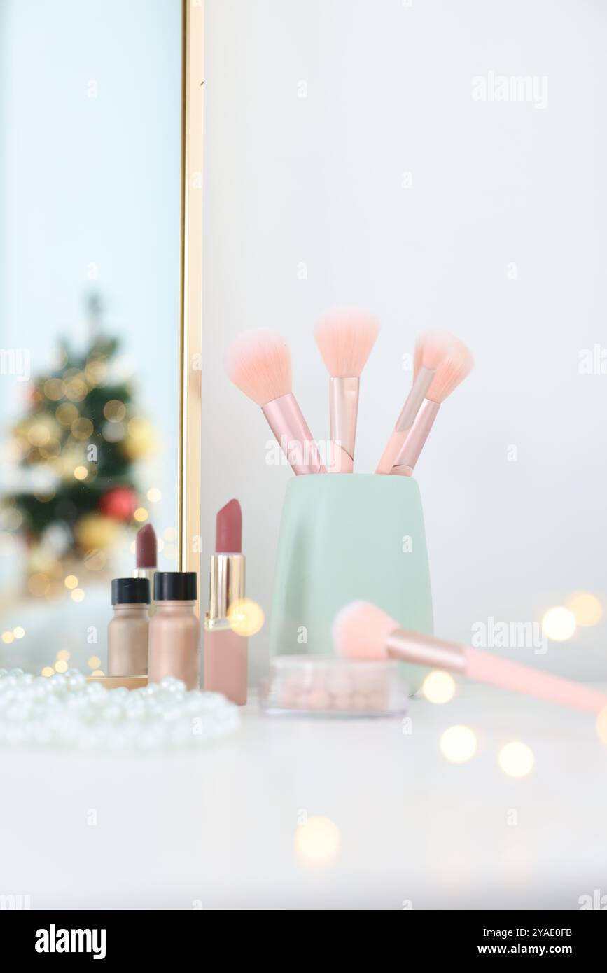 Makeup brushes, cosmetics and mirror on white table indoors Stock Photo