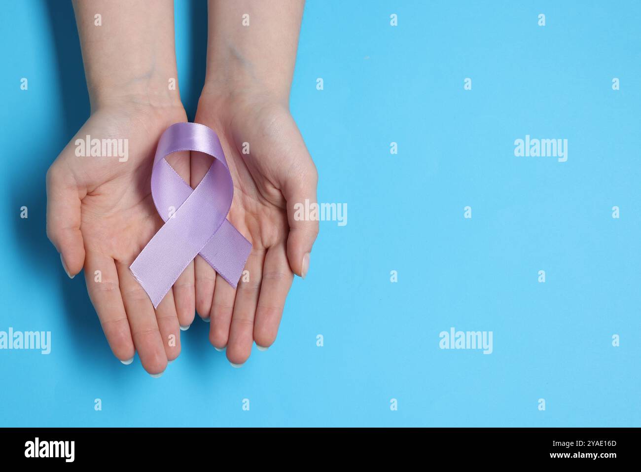 Woman with violet ribbon on light blue background, top view with space ...