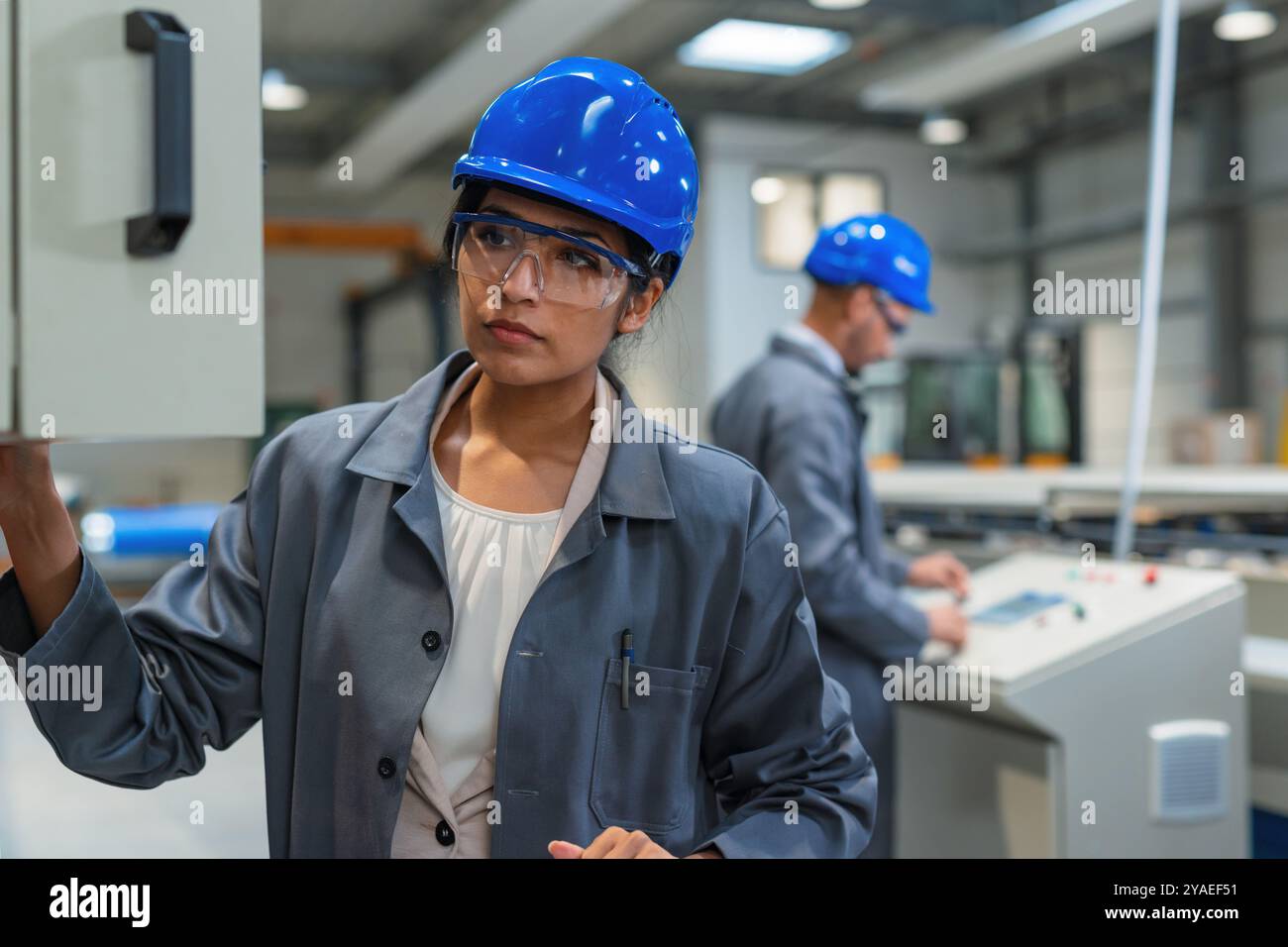 Two engineers, an Indian woman, and African American man, supervising ...