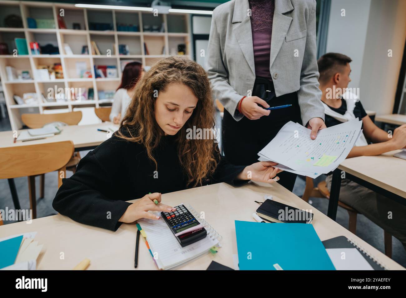 Engaged students learning in a modern classroom setting with a teacher Stock Photo