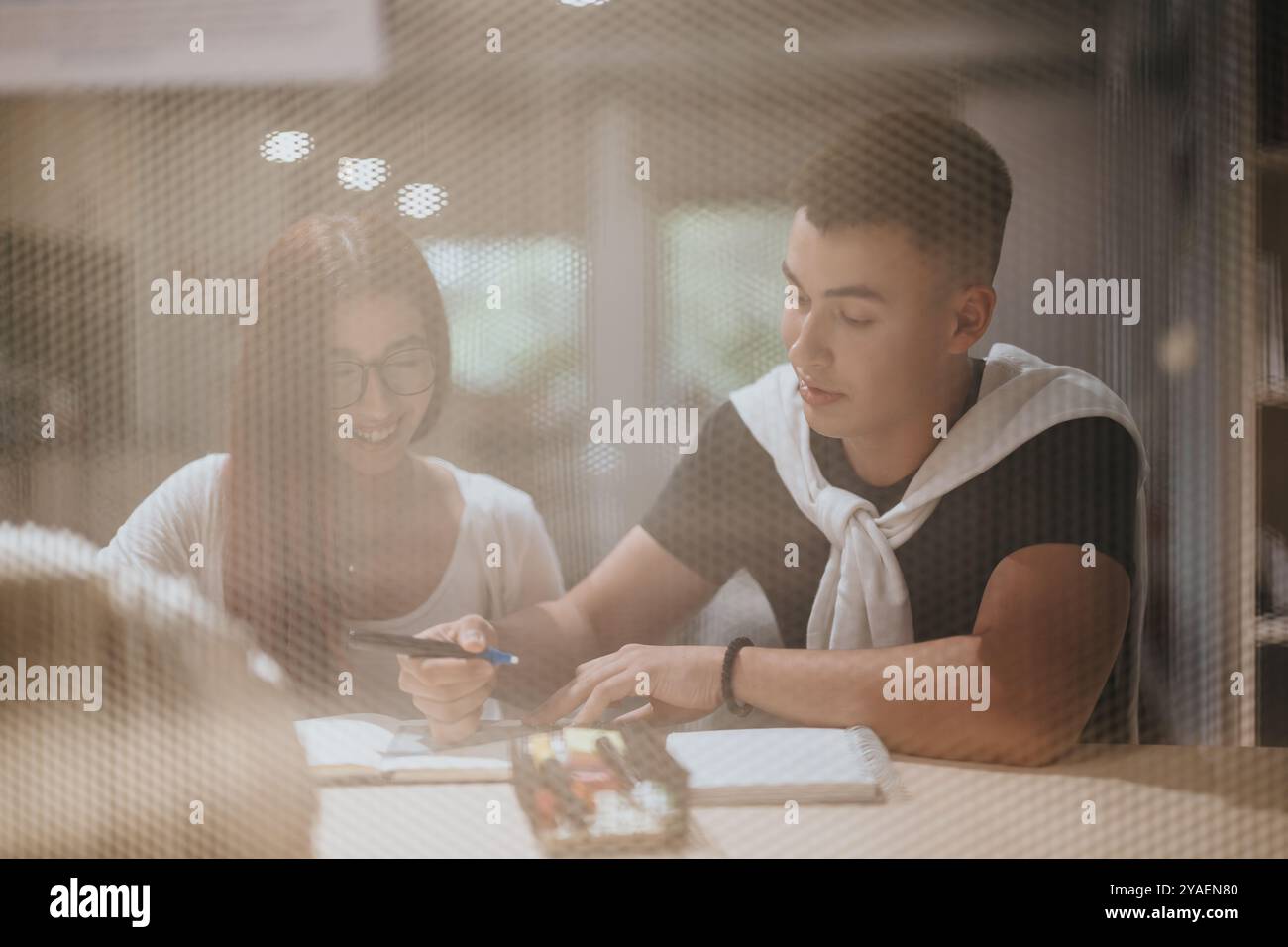 Students collaborating on project in library setting through window Stock Photo
