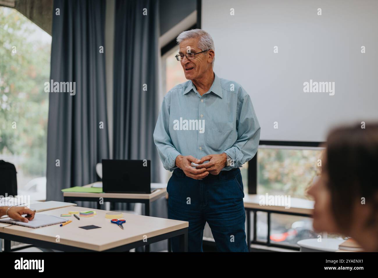 Elderly professor engaging with students in classroom setting Stock Photo