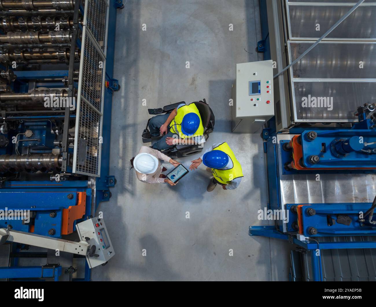 Female manager talking with two workers on the factory line, including one with a disability, about the production process, aerial shot. Stock Photo