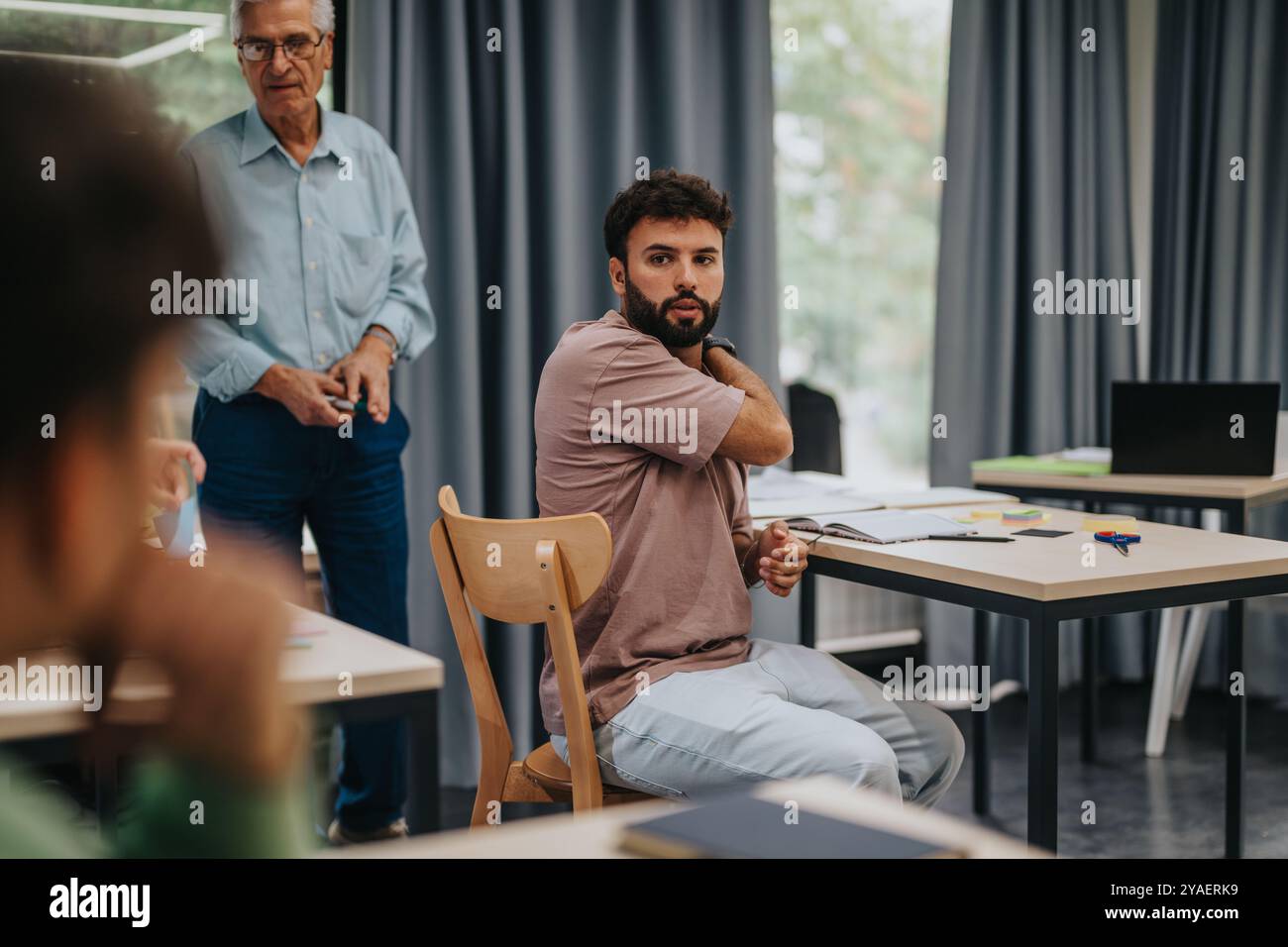 Elderly professor engaging with students in modern classroom setting Stock Photo