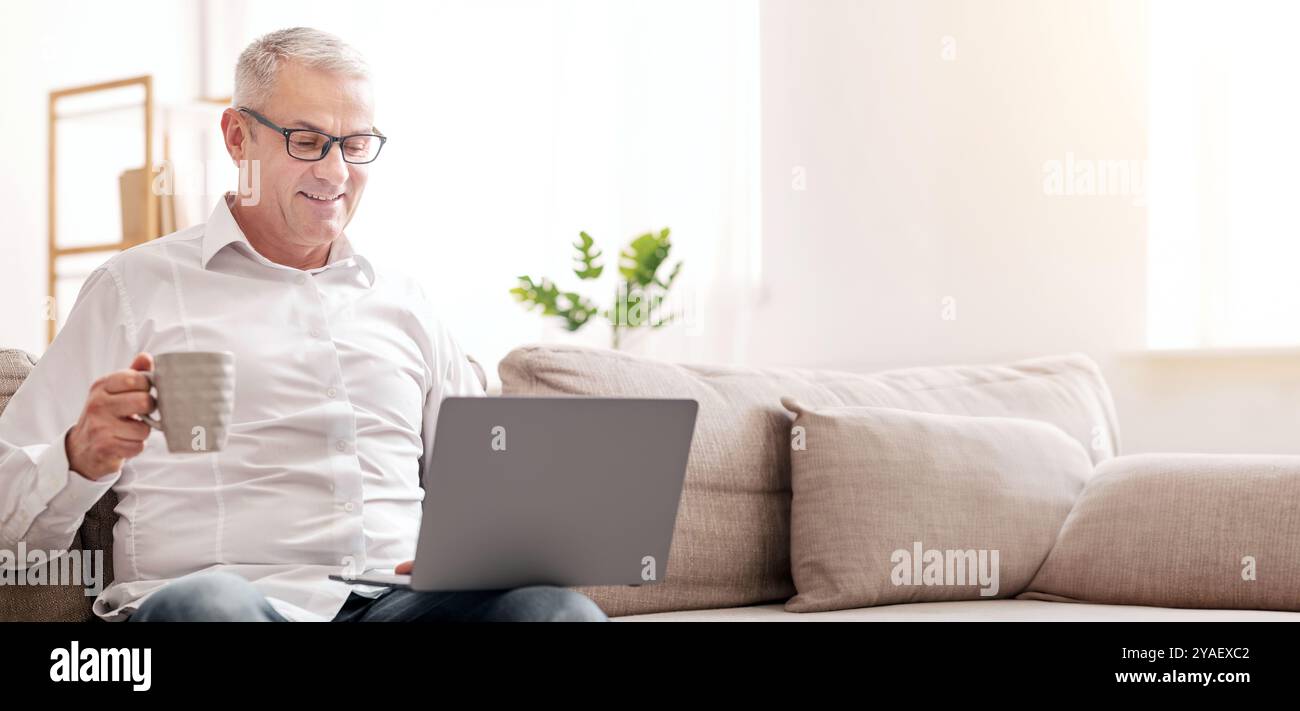 Elderly Man Using Laptop And Having Coffee Stock Photo