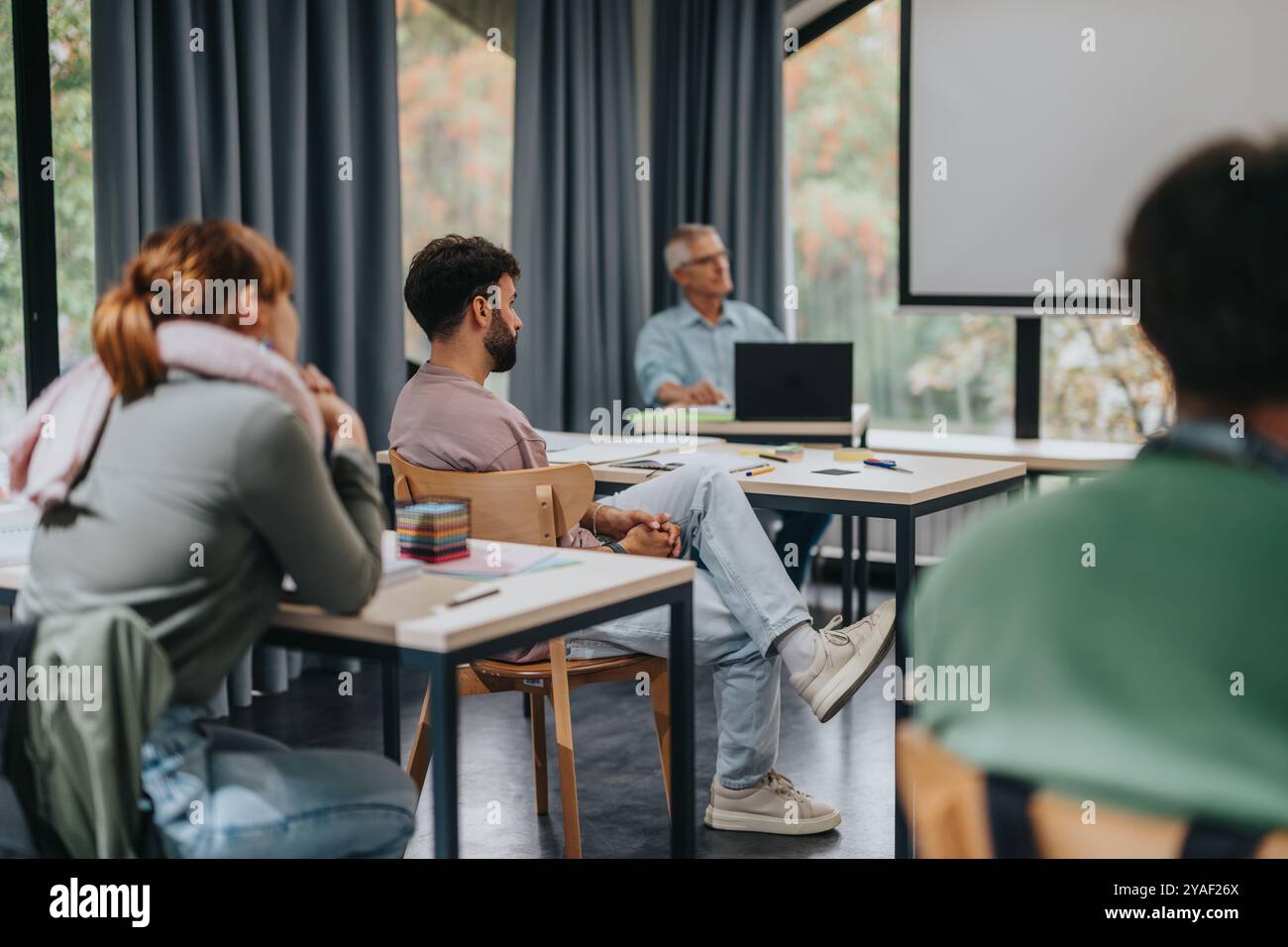 Students engaged in classroom lecture with elderly professor Stock Photo