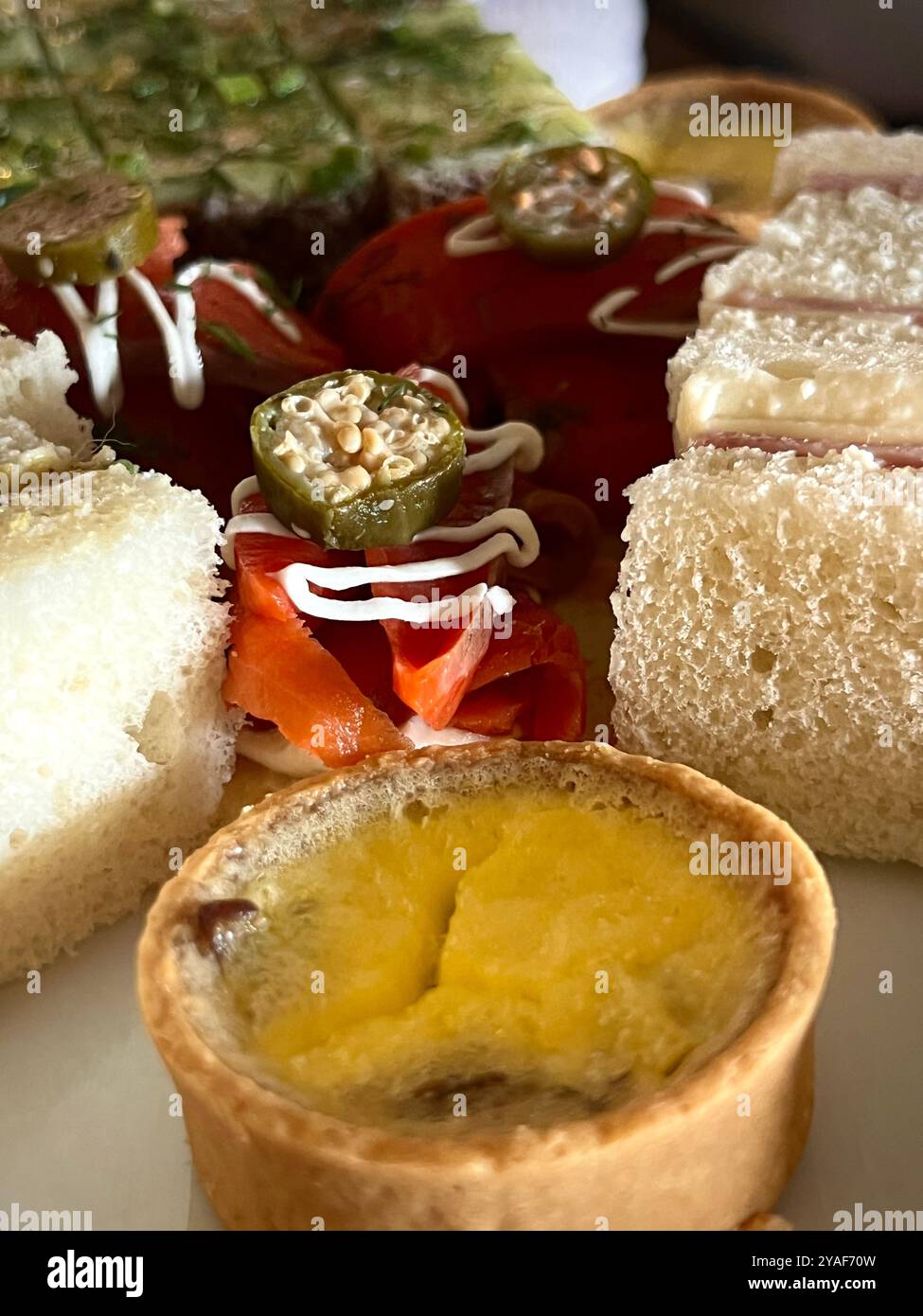 A selection of savory bites, including smoked salmon, quiche, and ham sandwiches, served during High Tea at the Empress Hotel - Smartphone Captured Stock Image