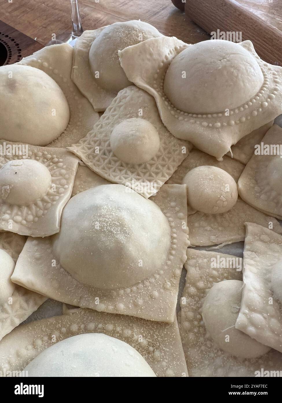 Close-up of freshly made ravioli, showcasing intricate pasta details in a rustic kitchen setting, ready for cooking - Smartphone Captured Stock Image