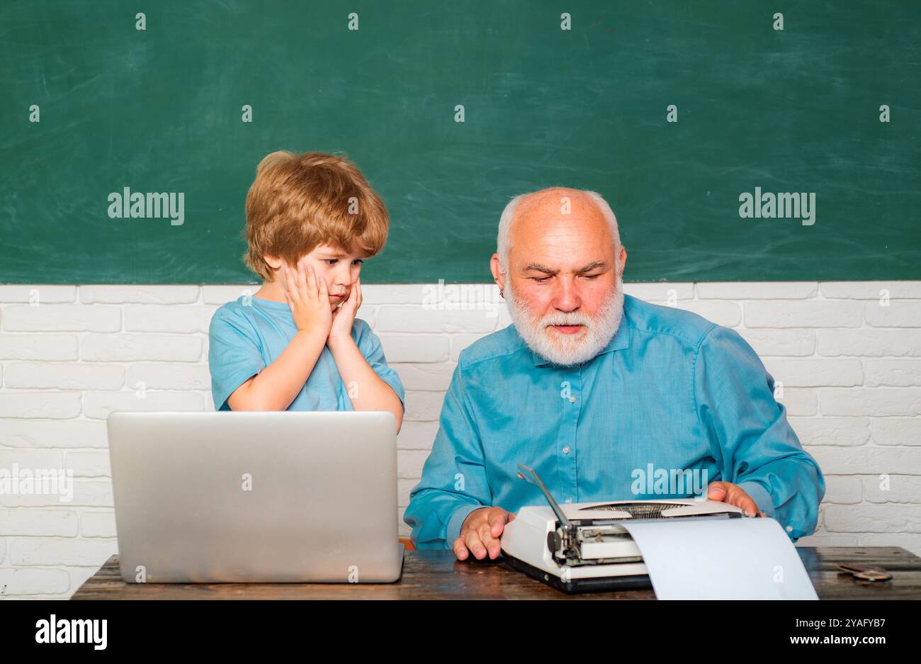 Elementary school kid and teacher with laptop in classroom at school ...