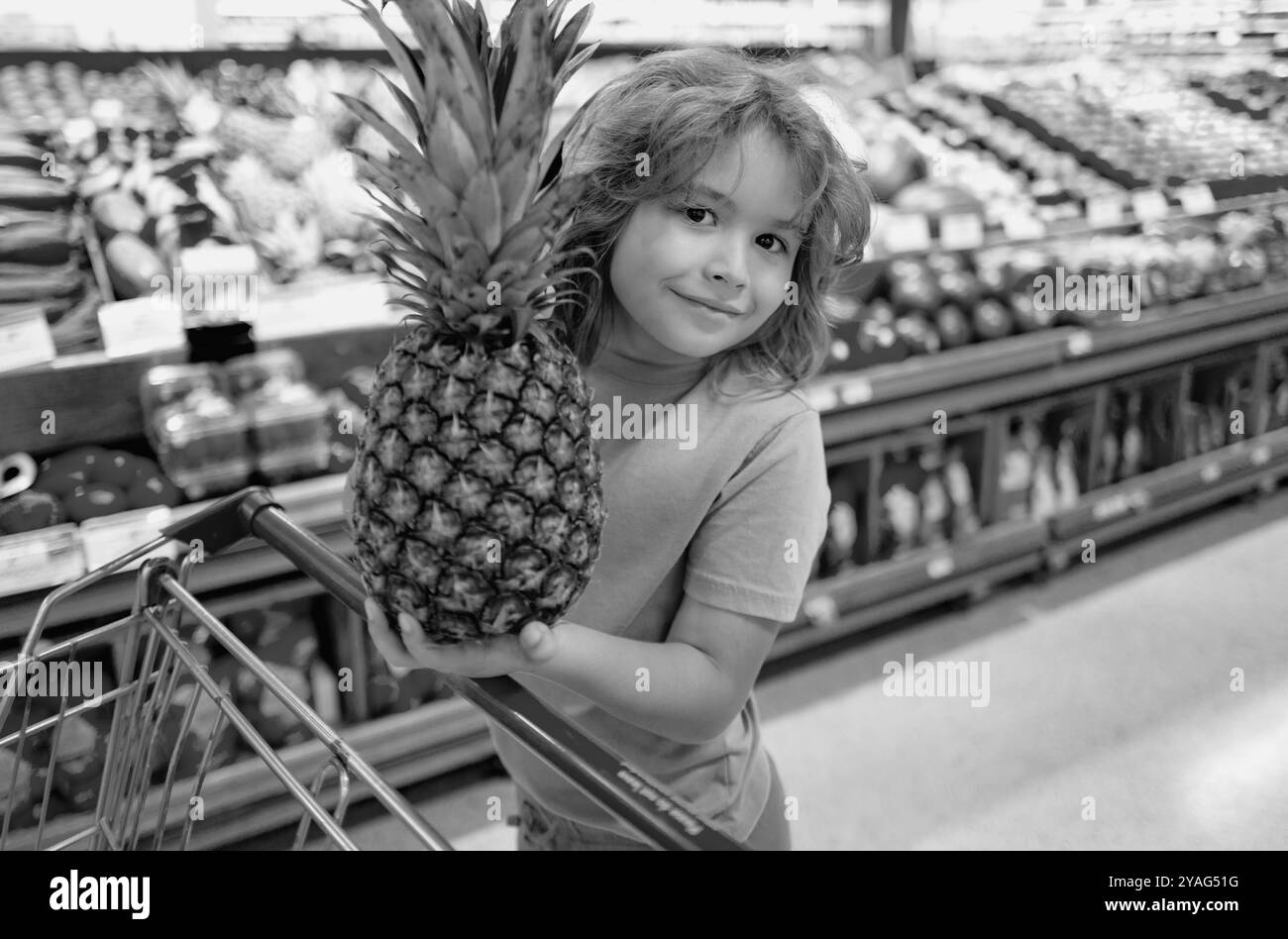 Happy little kid with fruits and vegetables at grocery store. Healthy food for young family with kids. Happy child with shopping cart full of fresh Stock Photo