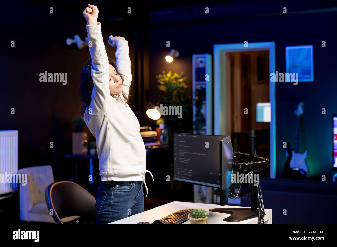 Developer doing software quality assurance, stretching after reading source code, feeling tired. IT admin relaxing muscles after inspecting coding to fix potential issues all day Stock Photo