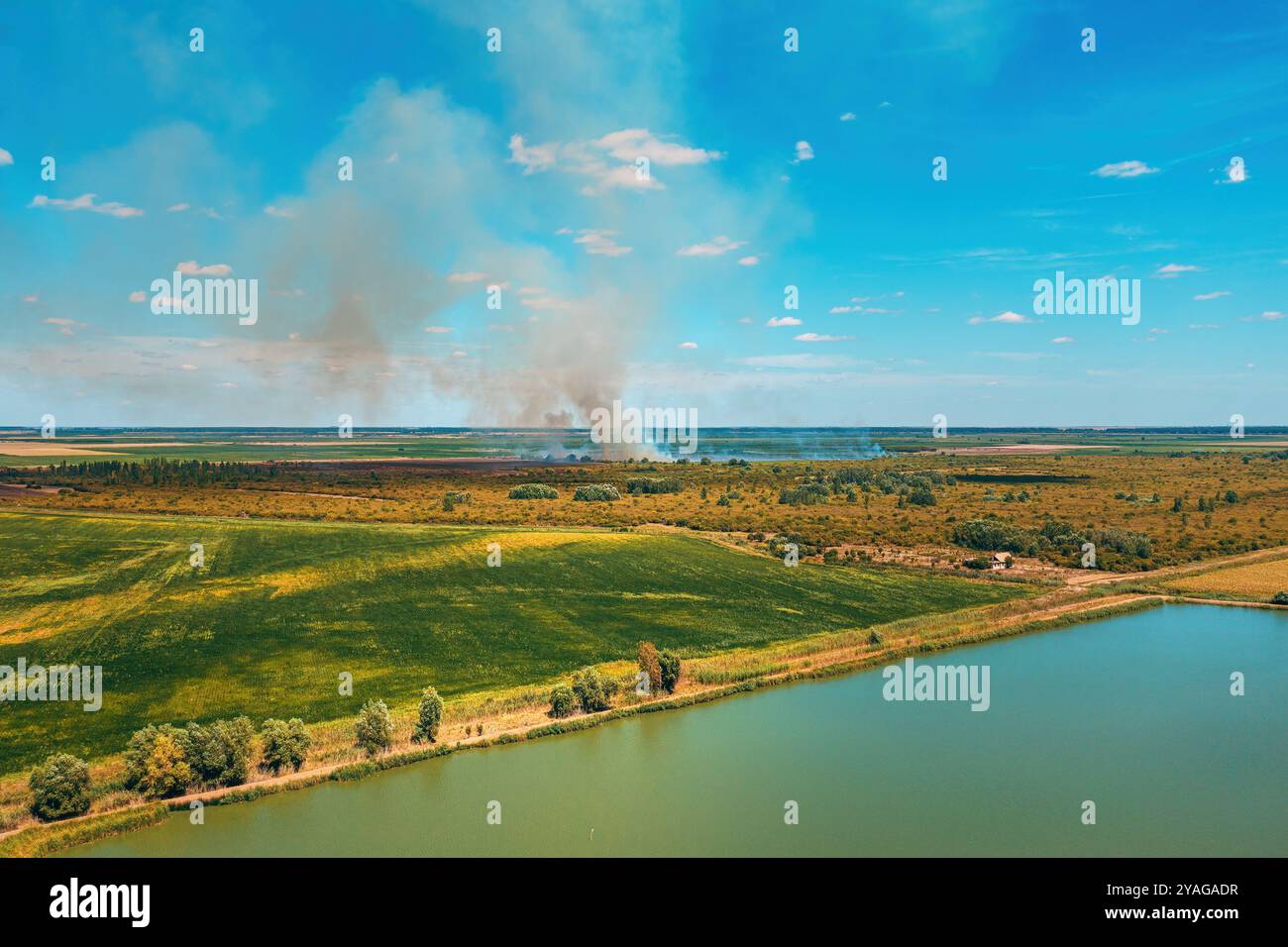 Drone pov aerial shot of wildfire burning in countryside landscape, thick white grey smoke rising up in the air, selective focus Stock Photo