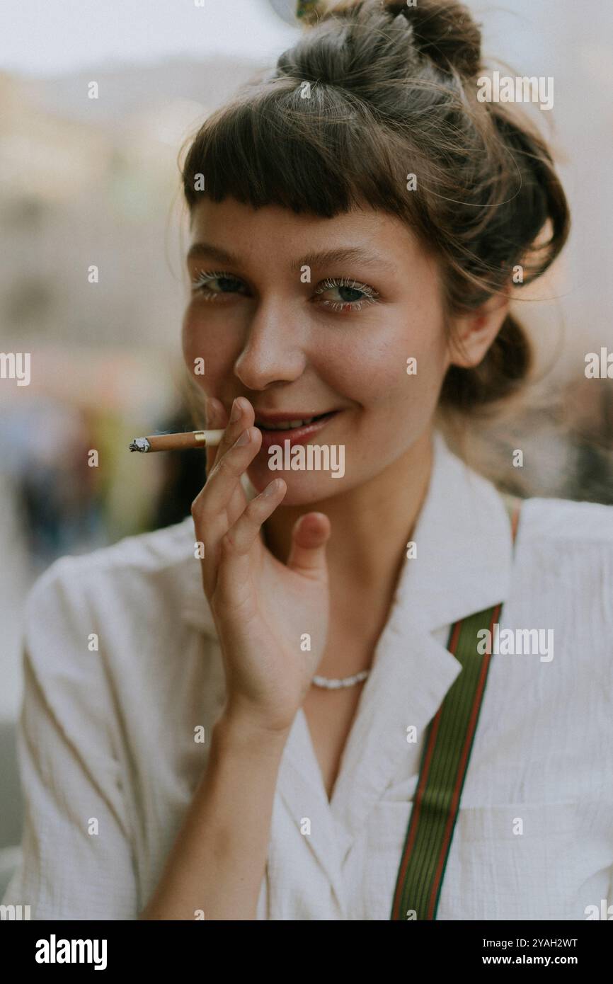 Young stylish woman smokes a cigarette on the street. Stock Photo