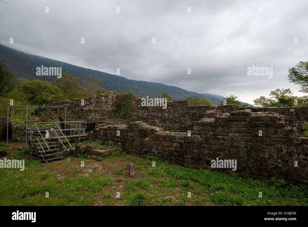 Stone wall at the ruins of the ancient castle of Meduno in Friuli Venezia Giulia. It is under restoration. There is a metal scaffold on the left. Stock Photo