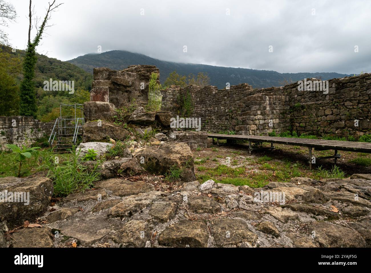 Stone wall at the abandoned ruins of the castle of Meduno in the Friuli  region (Italy). It is under restoration in a dramatic autumn day with fog. Stock Photo