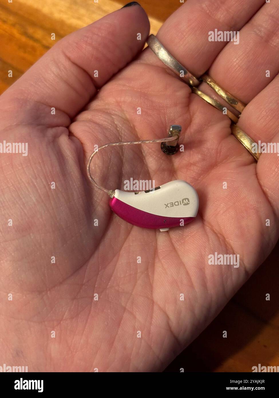 New bluetooth hearing aid in hand pink - widex model - Smartphone Captured Stock Image