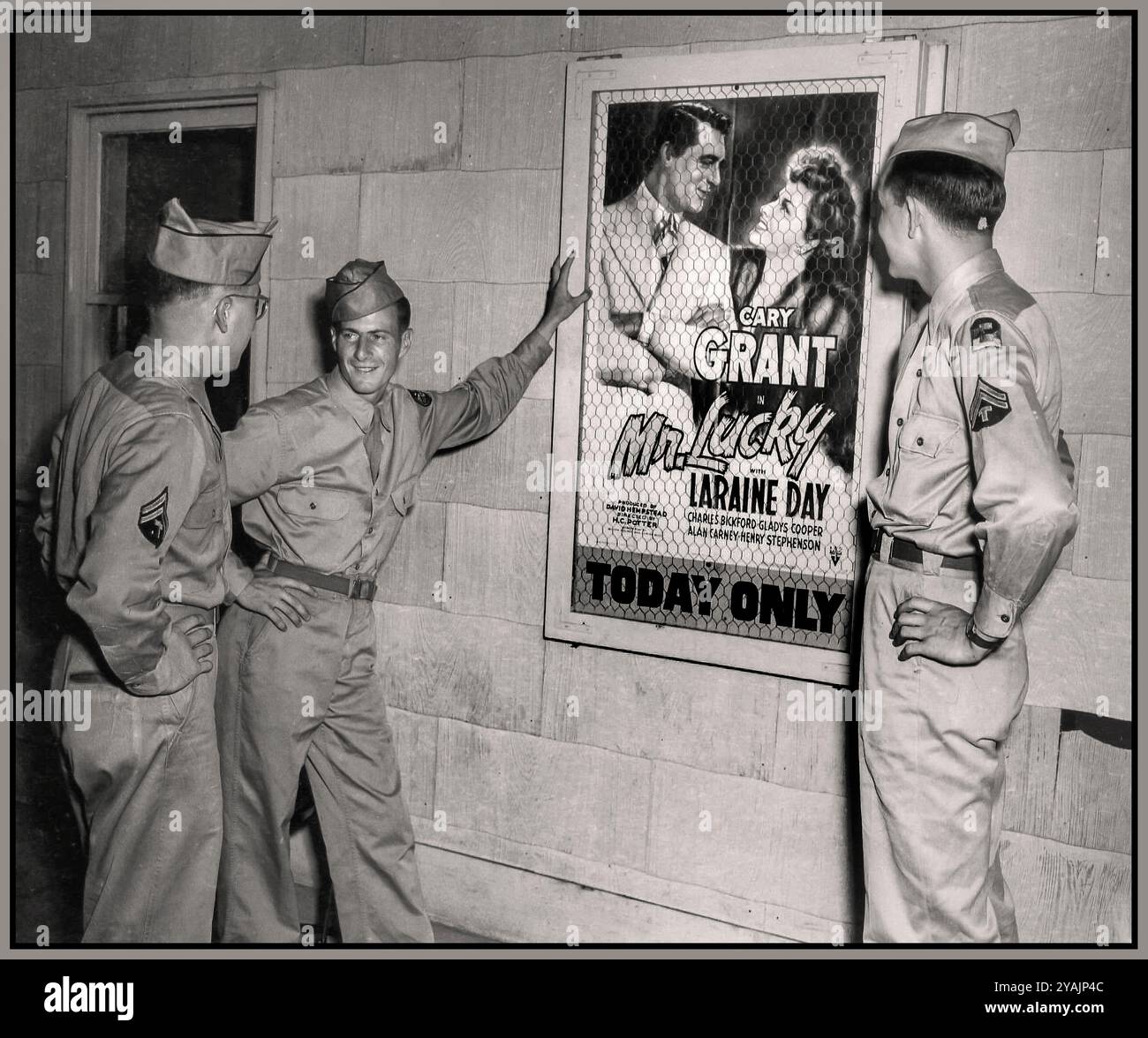 WW2 Entertaining the troops 'Going to the movies' Three male American servicemen in uniform chatting in front of a movie poster for the Cary Grant film, 'Mr. Lucky' at one of six movie theaters at Camp Atterbury, Indiana during World War II  July 1943 , at Camp Atterbury, Indiana, American servicemen stationed at the base had a rare opportunity to relax and enjoy some entertainment during the harsh realities of World War II. Three male servicemen in uniform were captured chatting in front of a movie poster for the Cary Grant film, 'Mr. Lucky', Stock Photo