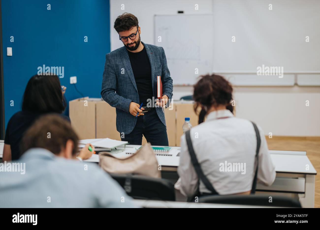 Professor assisting students during an engaging classroom session Stock Photo