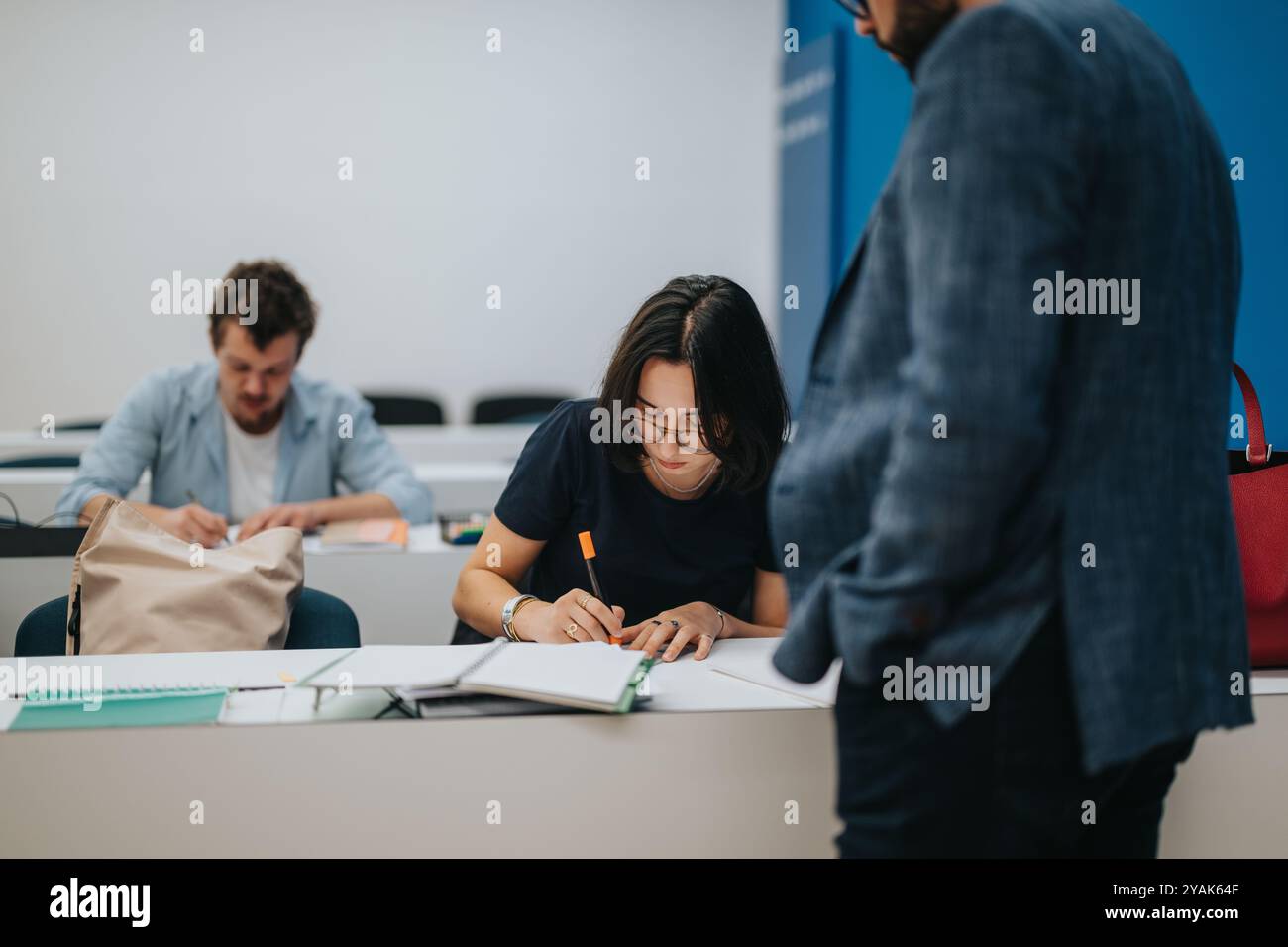 Professor assisting students during an engaging classroom session Stock Photo