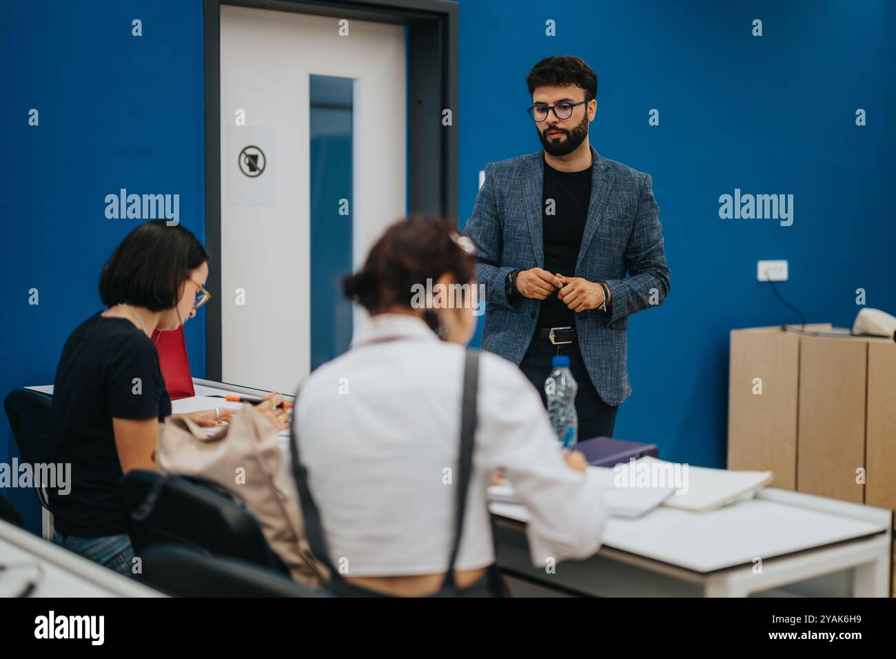 Professor assisting students during a class in modern classroom Stock Photo