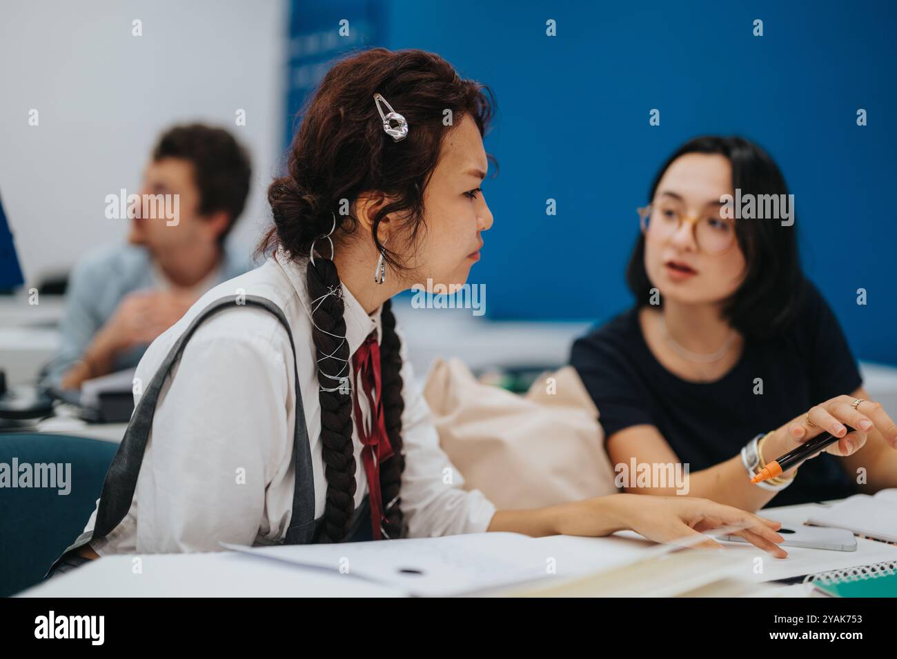 Engaged students collaborating on class tasks with professor assistance Stock Photo