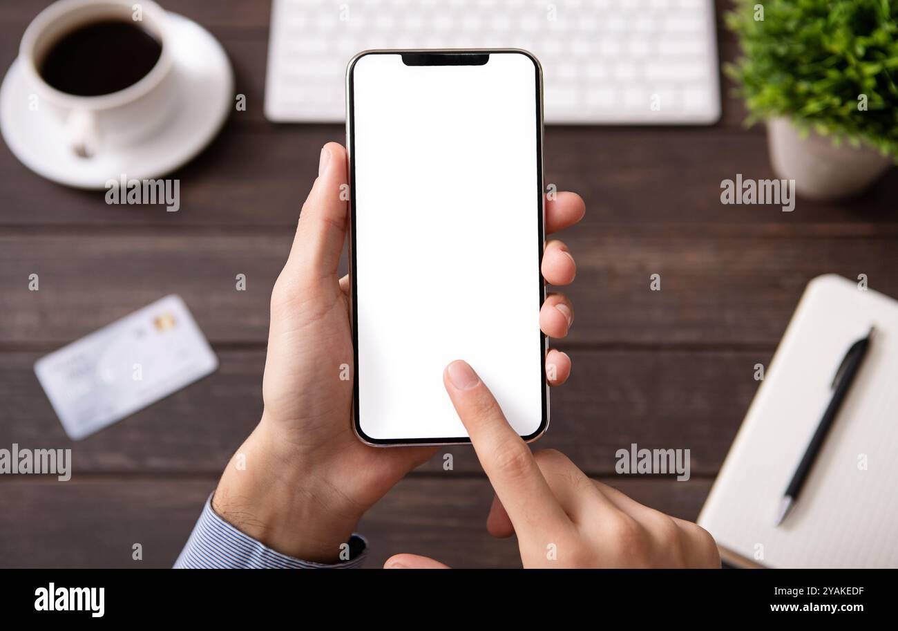 Man using blank smartphone on workplace desk Stock Photo
