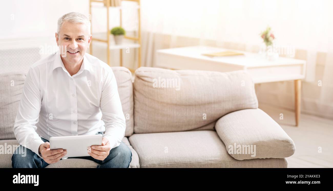 Senior man using digital tablet looking at camera Stock Photo
