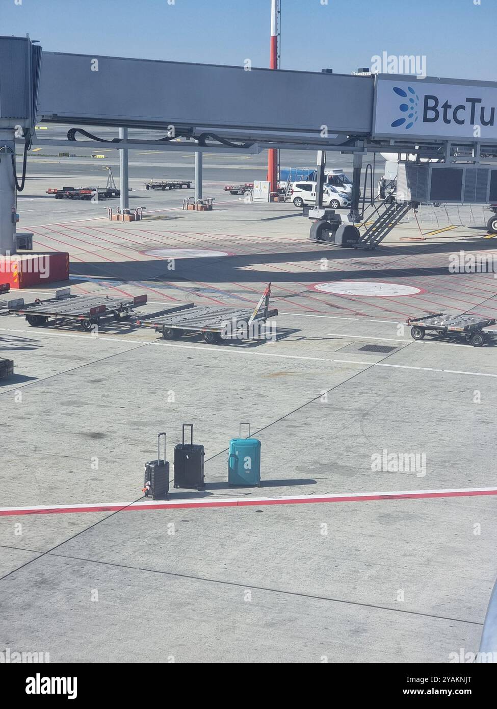 Three lonely (abandoned?) suitcases left behind on an airport apron (tarmac); lost baggage concept, delayed luggage concept - Smartphone Captured Stock Image