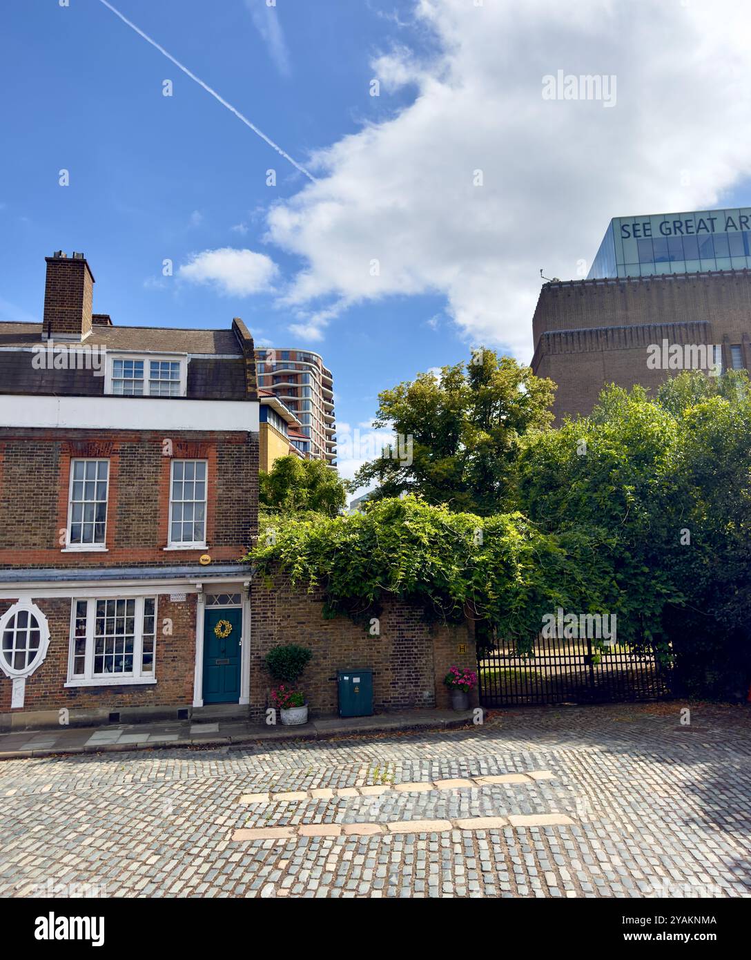 A picturesque brick townhouse with a teal front door, adorned with a decorative wreath, set along a cobblestone street. The classi architecture is com - Smartphone Captured Stock Image