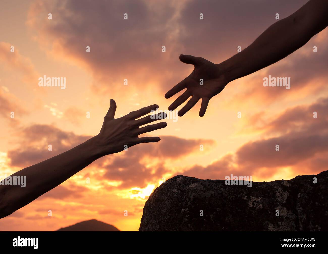Giving a helping hand up a mountain. Helping someone in need concept. Stock Photo