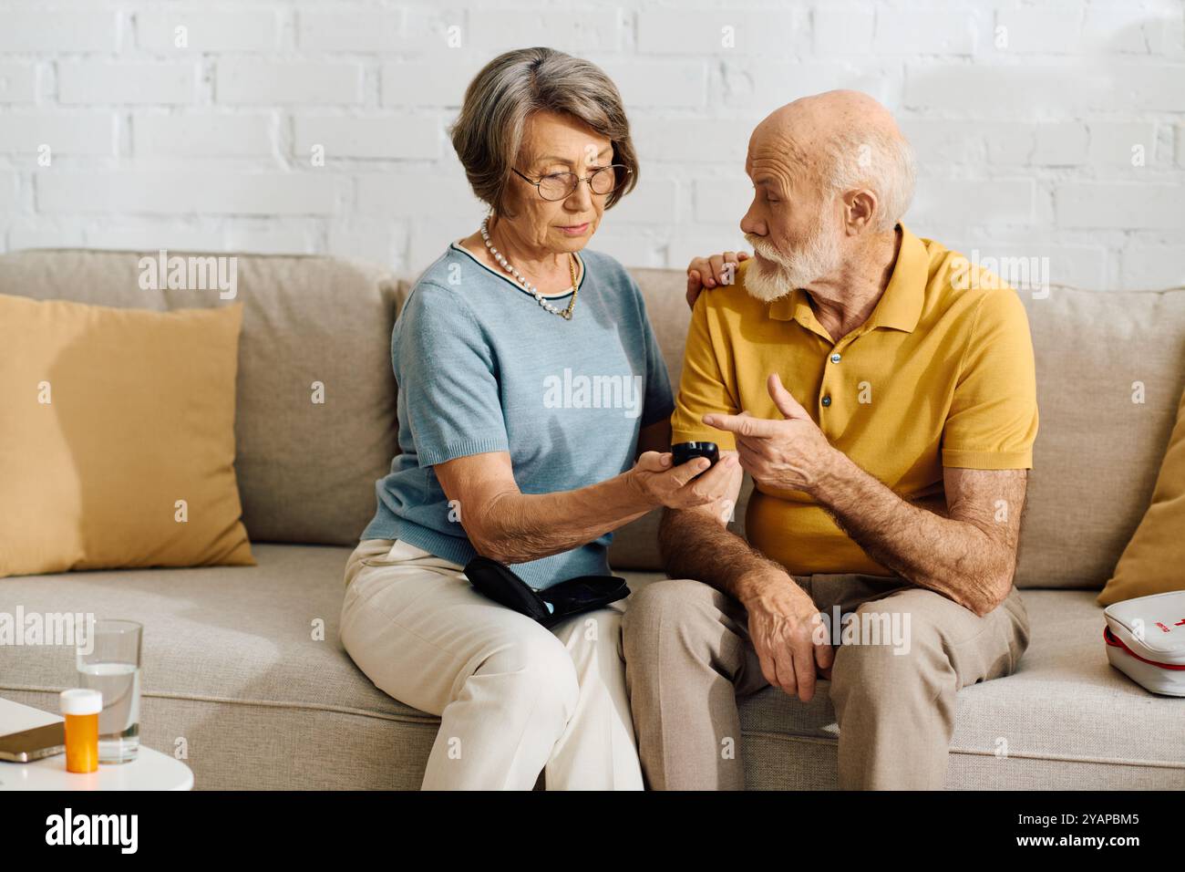 A loving couple shows support as the wife helps her diabetic husband with his health monitor. Stock Photo