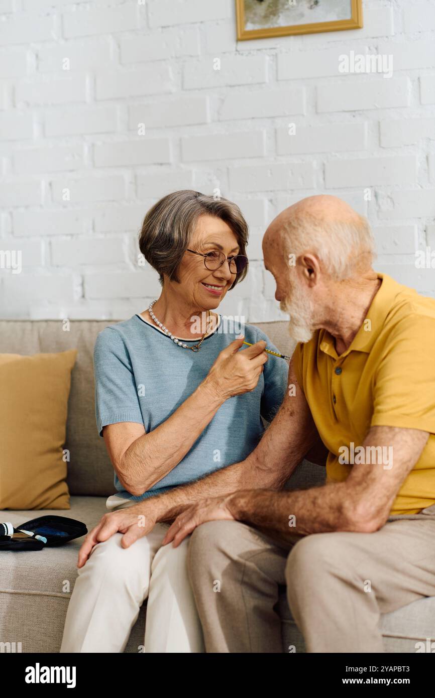 A senior couple enjoys a warm moment at home the wife supports her diabetic husband. Stock Photo