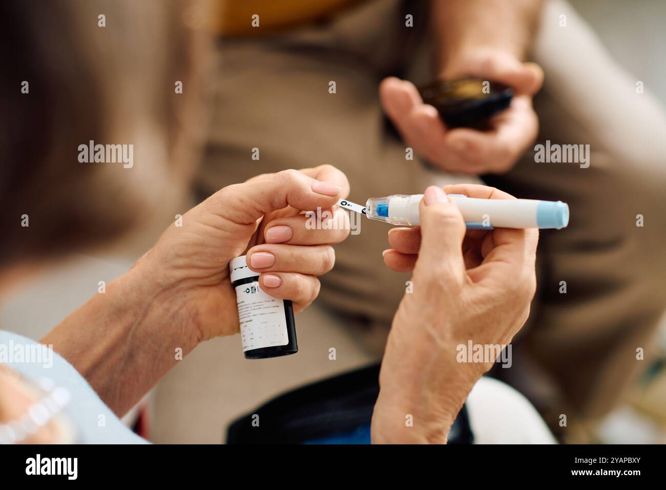 A supportive wife assists her husband as he prepares his diabetes medication at home. Stock Photo