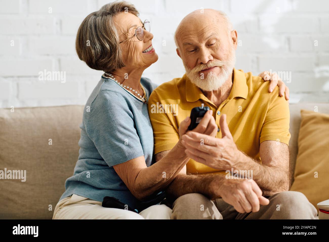 A caring wife assists her diabetic husband in their cozy living room, showcasing love and support. Stock Photo