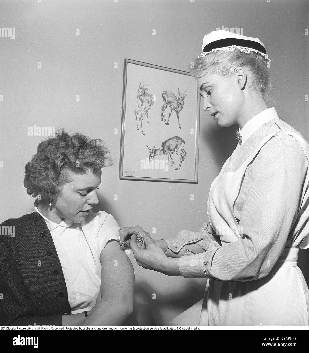 Vaccines in the 1950s. A nurse sticks a syringe in the arm and vaccinates a female patient. 1958. Kristoffersson ref CC37-10 Stock Photo