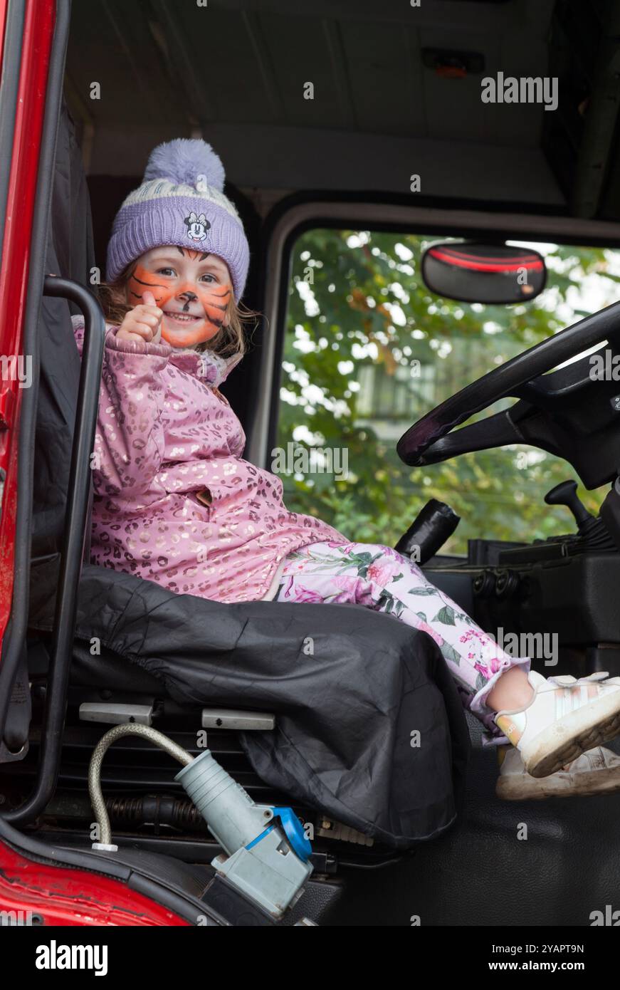 Young girl sitting in a fire engine with a painted face Stock Photo