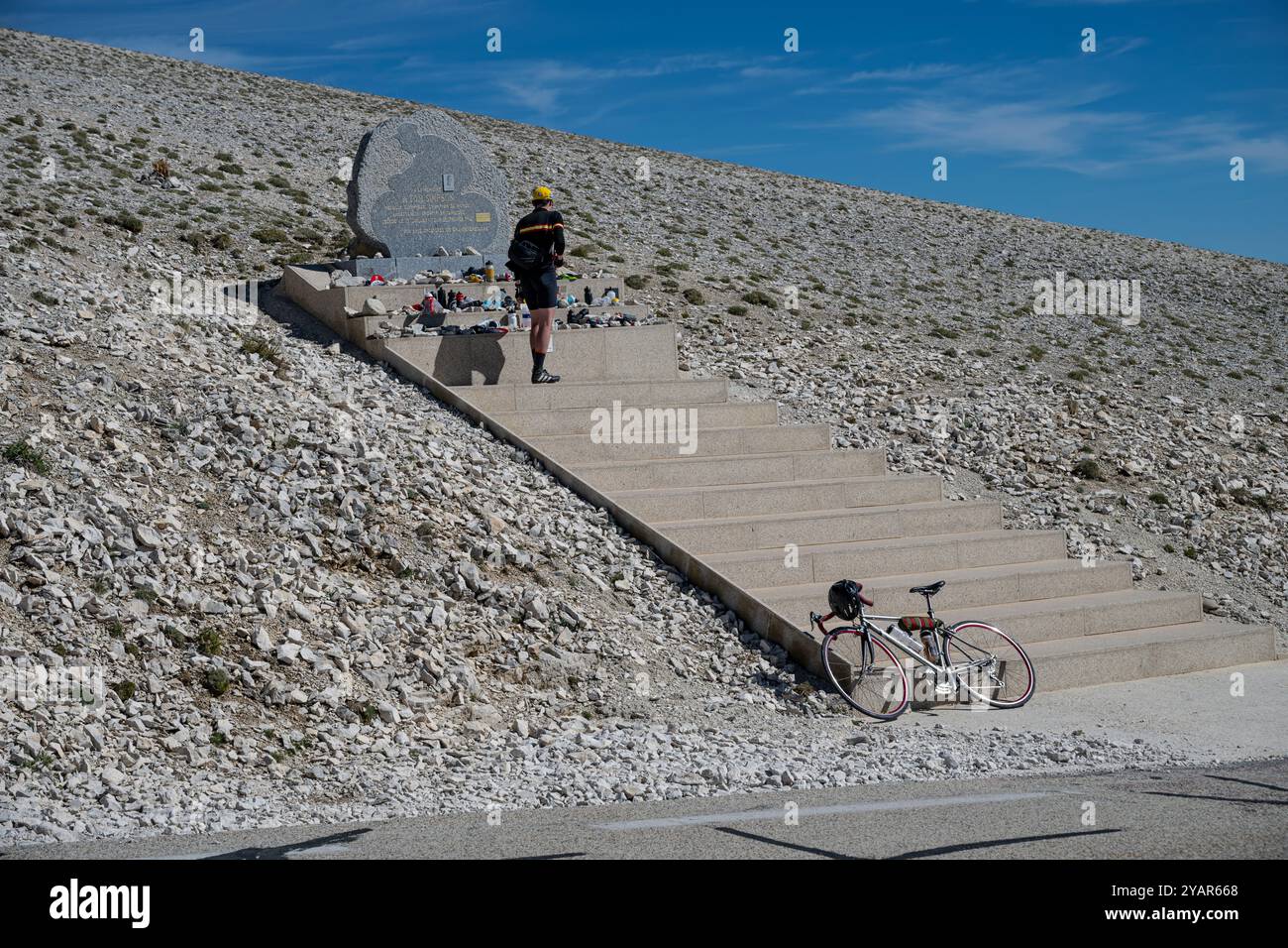 Male road cyclist takes a minute to pay his respects at the Tom Simpson memorial on Mont Ventoux, Provence, France. Stock Photo