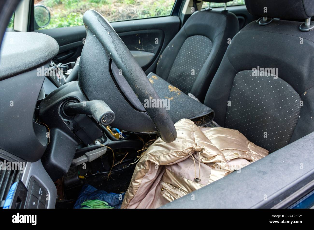 Voiture complètement vandalisée, les fenêtres sont brisées et des vêtements traînent encore sur les sièges | Vandalised car where the windows are brok Stock Photo